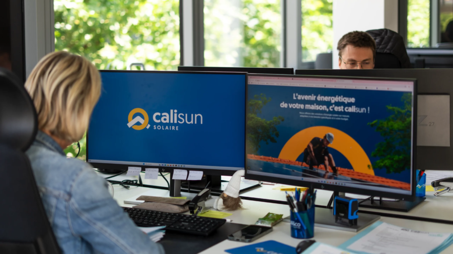 Postes de travail dans un bureau avec deux écrans affichant le logo CaliSun Solaire et une page web sur l’énergie solaire.